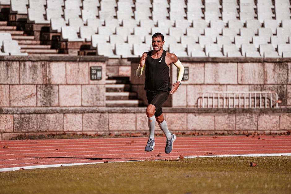 A determined male athlete sprinting on an outdoor track, showcasing endurance and fitness.
