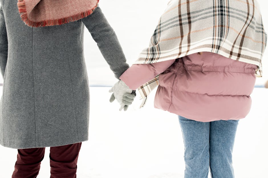 A couple holding hands outdoors in winter attire, showcasing warm clothing essentials.