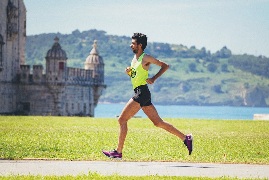 Full body of young active male runner in sportswear jogging on track near lake and ancient palace during outdoor workout