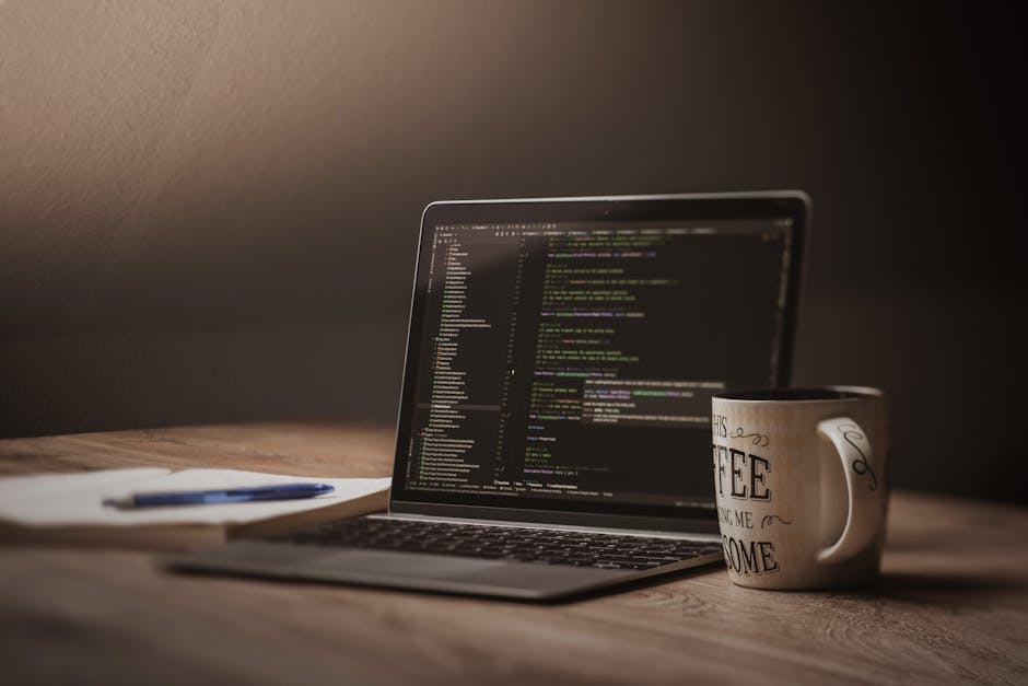 A comfortable workspace showcasing a laptop with code, a coffee mug, and a notepad.