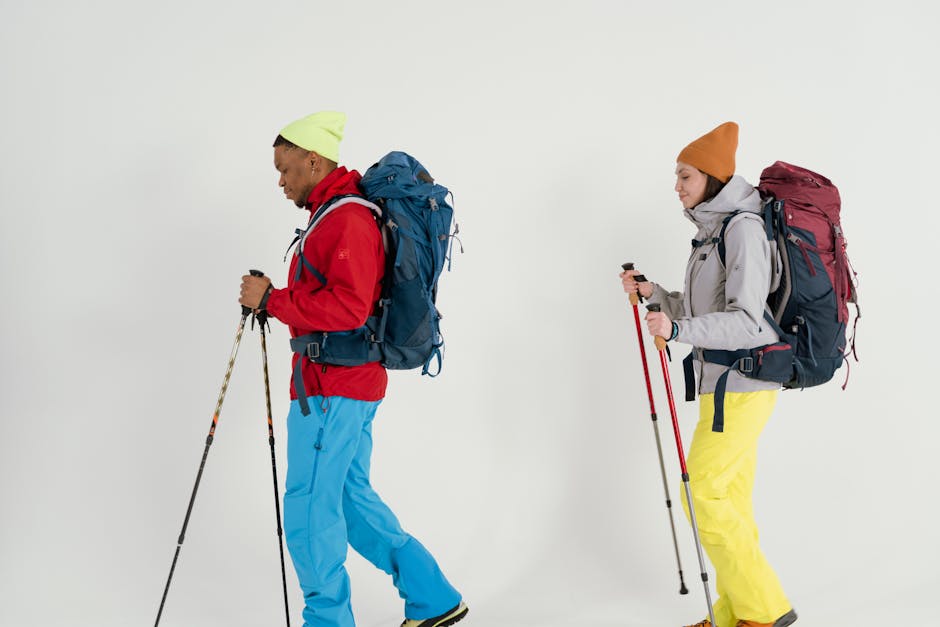 Studio shoot of two hikers with backpacks and hiking sticks on a white background.